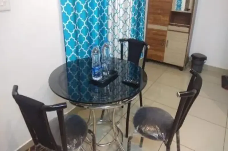 Cozy room seating area with glass table and chairs near balcony window at Thanal Farm Stay Vagamon