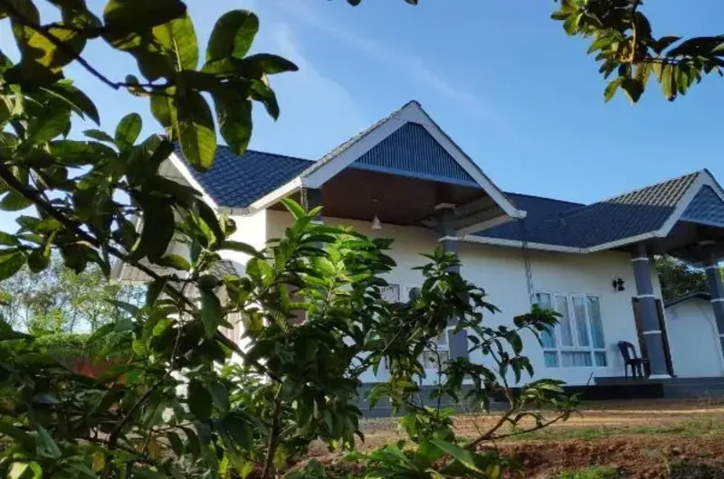 Exterior view of cottage building surrounded by green gardens at Thanal Farm Stay Vagamon