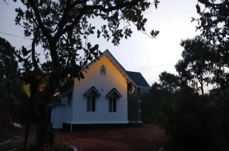 Cottage exterior perched on misty hill surrounded by lush green foliage at Thanal Farm Stay Vagamon