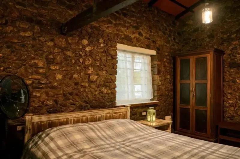 Rustic wooden bedroom interior with comfortable double bed and warm ambient lighting at Mountain Villa Vagamon