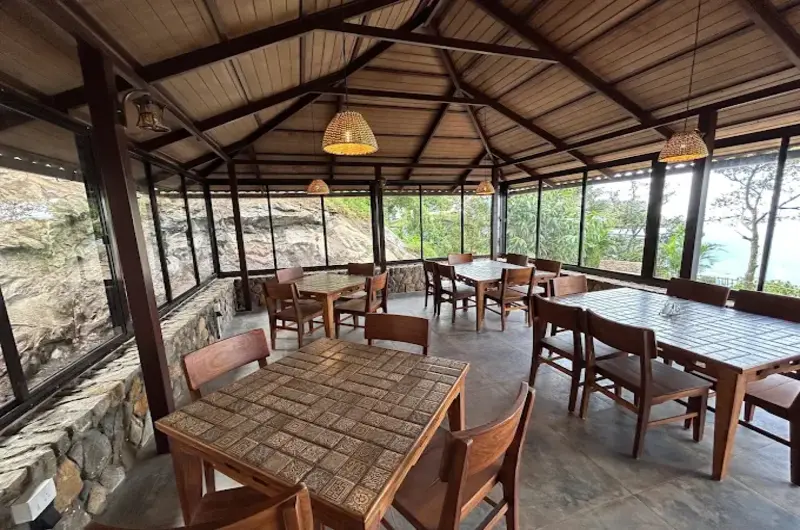 Rustic covered dining terrace with wooden tables and scenic mountain views at Mountain Villa Vagamon