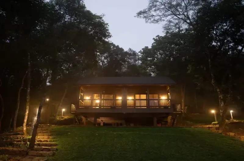 Warmly lit villa exterior surrounded by trees at dusk at Mountain Villa Vagamon