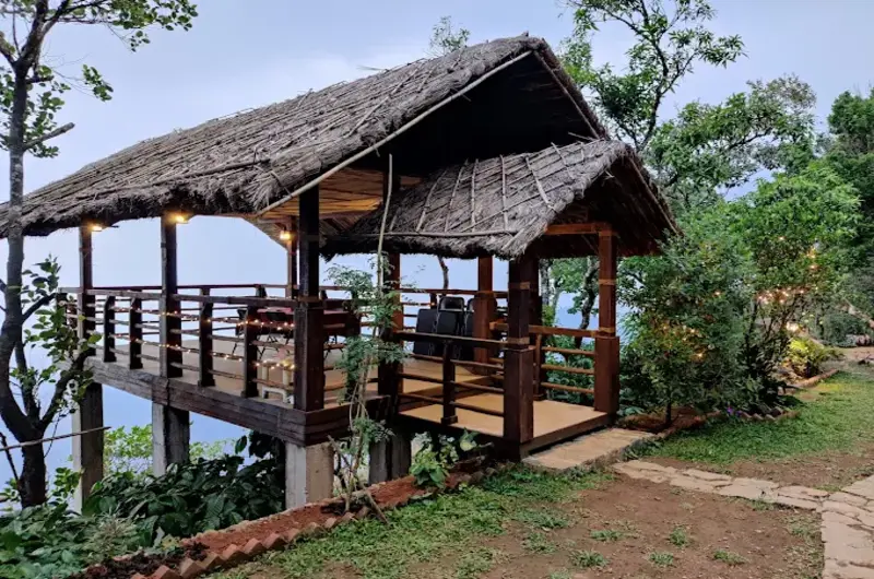 Wooden cottage structure on manicured green lawn at Mountain Villa Vagamon