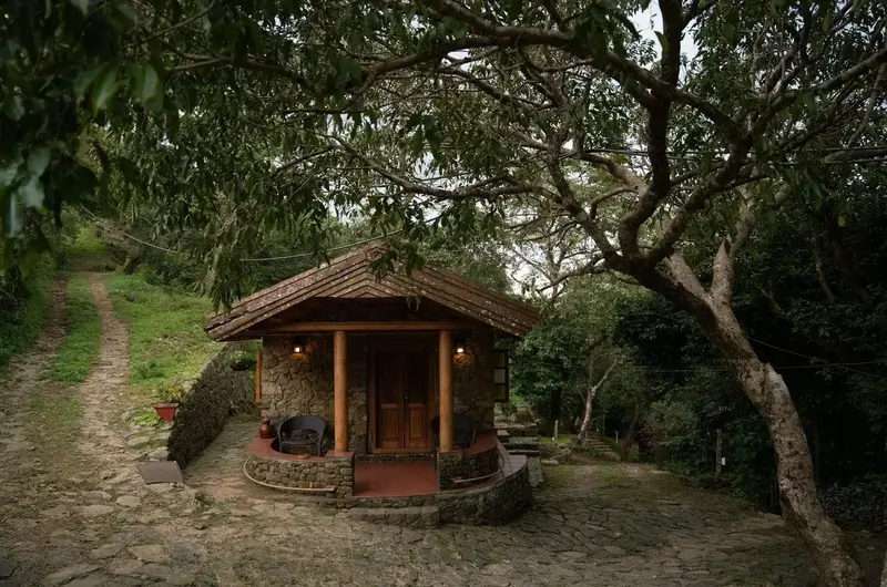 Warmly lit villa exterior surrounded by trees at dusk at Mountain Villa Vagamon