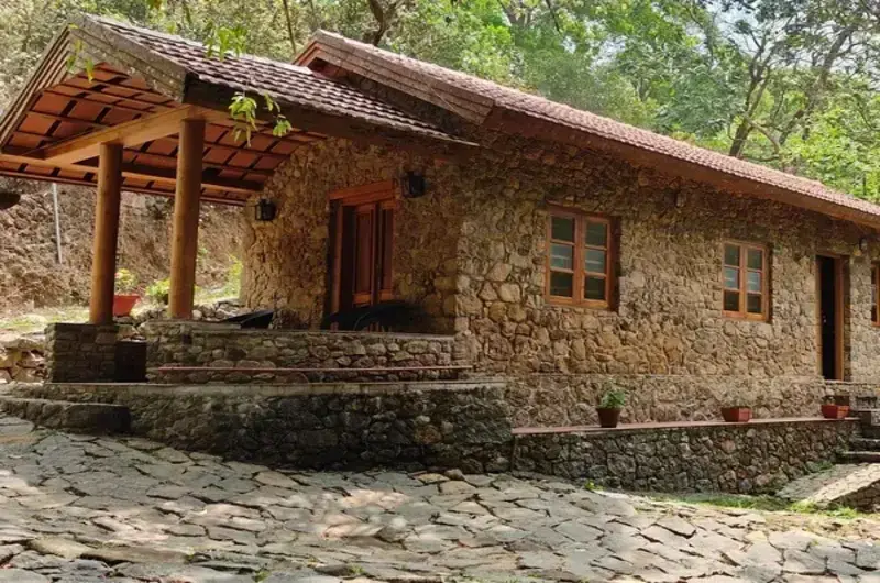 Covered outdoor dining terrace with rustic stone walls and wooden tables at Mountain Villa Vagamon