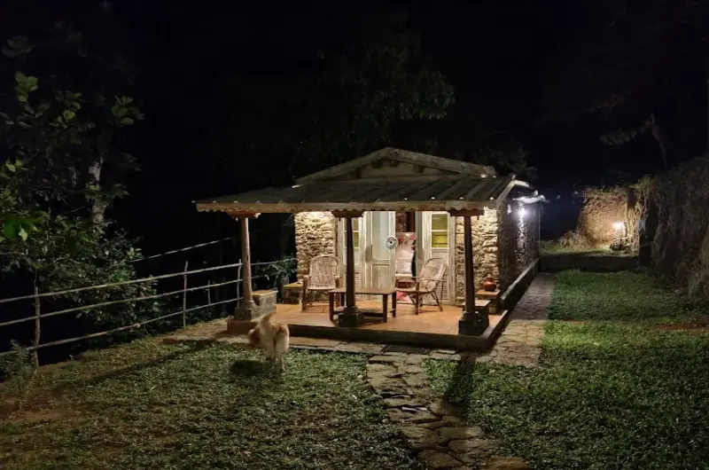 Illuminated wooden cottage on green lawn at night at Mountain Villa Vagamon
