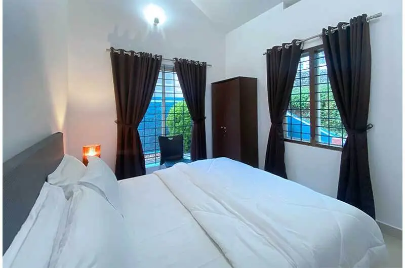 Spacious bedroom interior featuring comfortable double bed and curtained windows at Angel's Vagamon