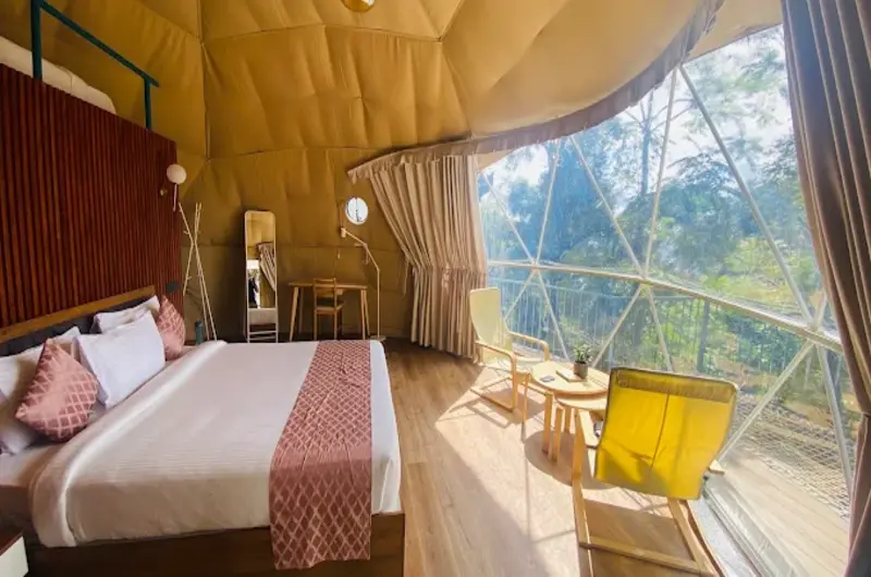 Spacious geodesic dome bedroom interior with double bed and seating chairs at Willmount Geodesic Domes Vagamon