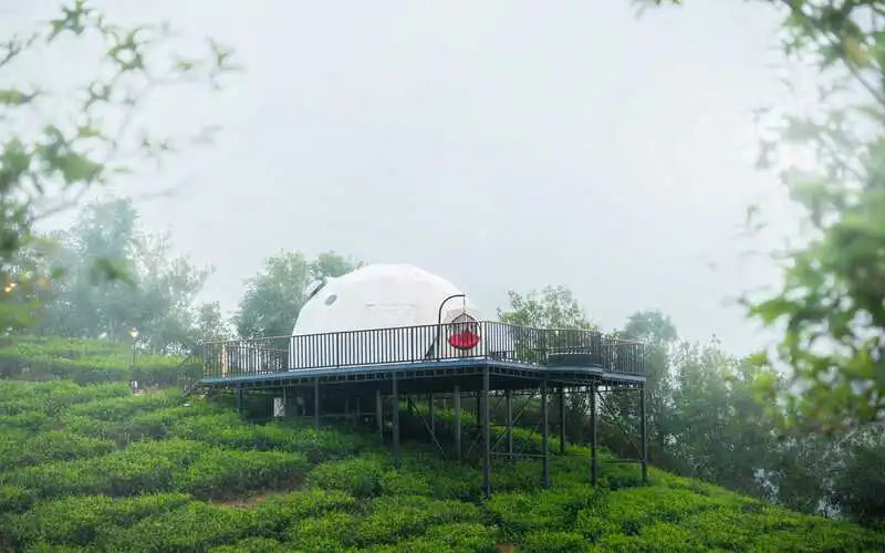 White geodesic glamping dome on hilltop overlooking misty mountains at Pendora Glamps Vagamon
