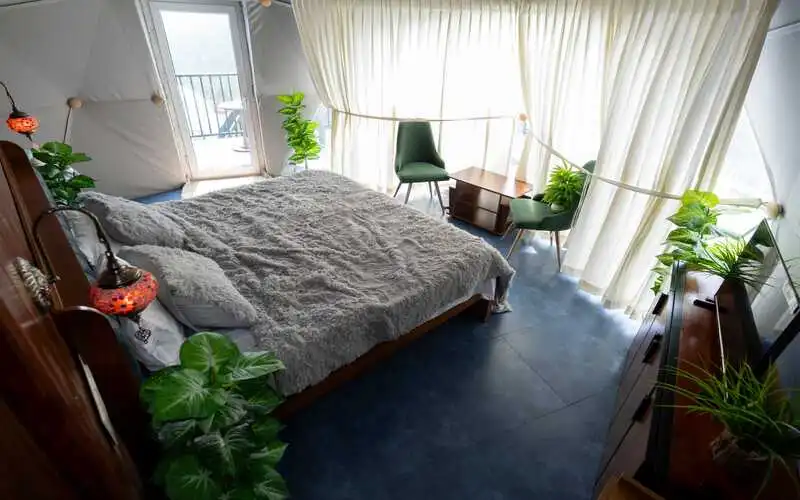Dome stay interior setup with double bed and mountain window view in Vagamon