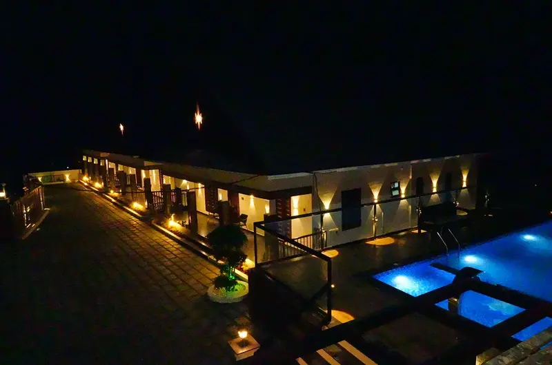 Panoramic night view of illuminated resort buildings and swimming pool