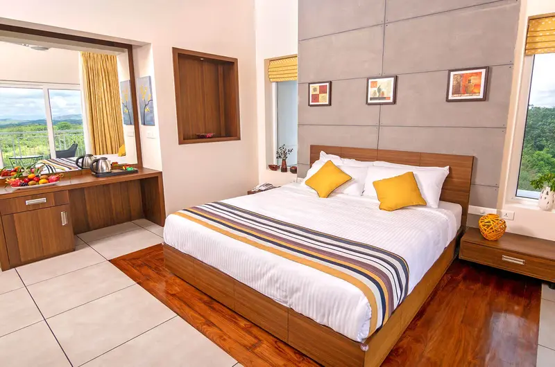 Spacious luxury guest room with king bed and balcony view at Le Collines Resort Vagamon