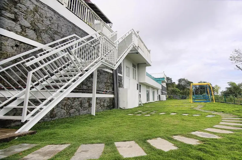 Exterior garden pathway leading to Le Collines Resort building in Vagamon