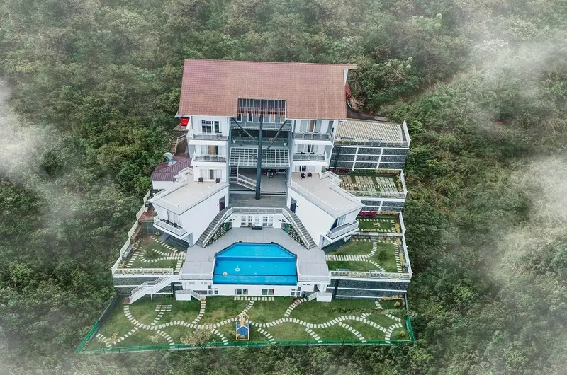 Aerial drone view of Le Collines Resort with outdoor swimming pool and hill station scenery