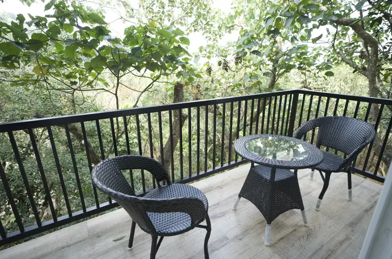 Private room balcony seating area overlooking lush green trees at Vanaheim Resort Vagamon
