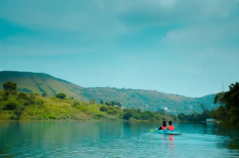 Boating on scenic lake with lush green mountain backdrop near Nexstay Mount Tales Vagamon