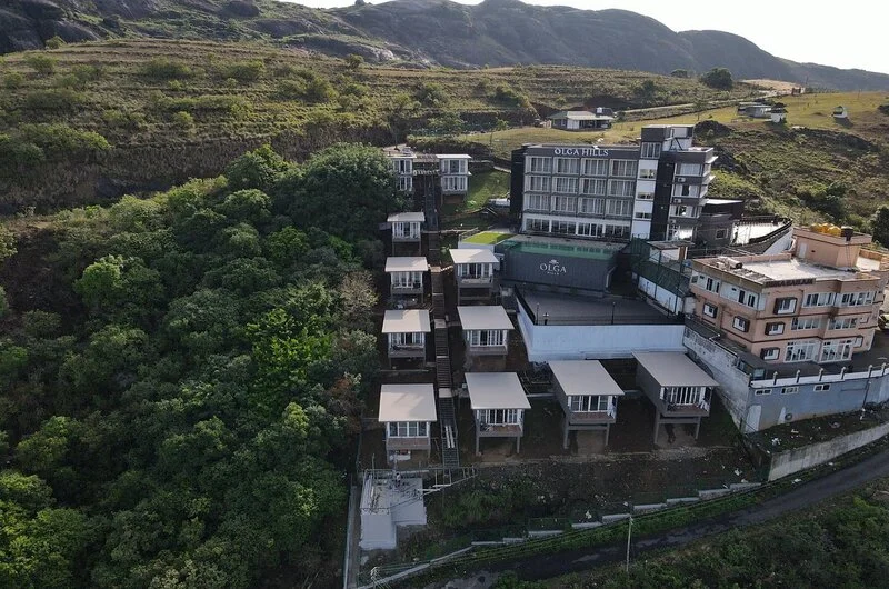 Aerial view of Olga Resorts complex nestled on green mountain slopes in Vagamon