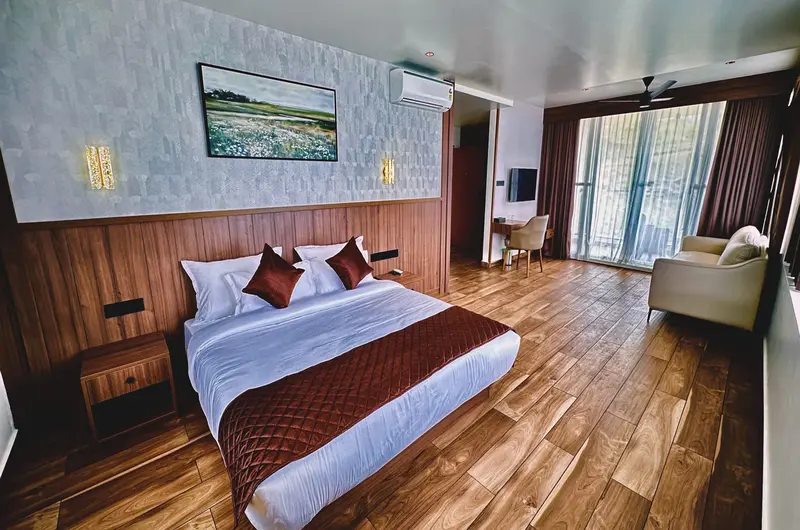Modern guest bedroom with wooden flooring and private balcony access at Olga Resorts Vagamon