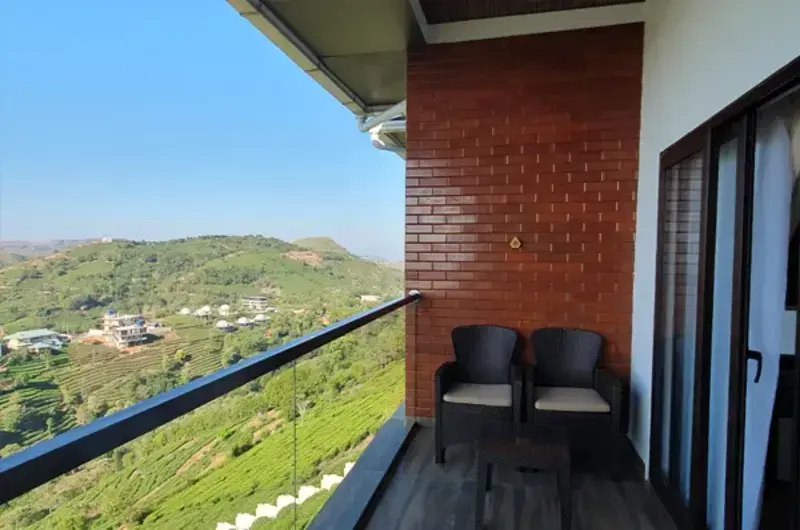 Private resort room balcony with seating and scenic valley view in Vagamon