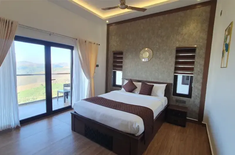 Modern resort suite bedroom with large bed and direct balcony access overlooking nature
