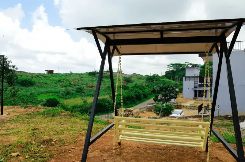 Outdoor wooden canopy swing in lawn area at Rock View Resort Vagamon
