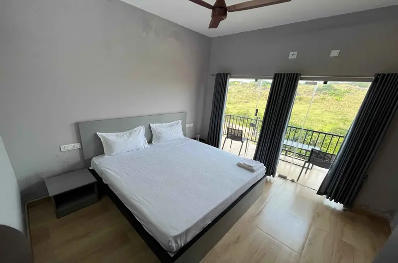 Modern deluxe room bedroom with balcony view at Rock View Resort Vagamon