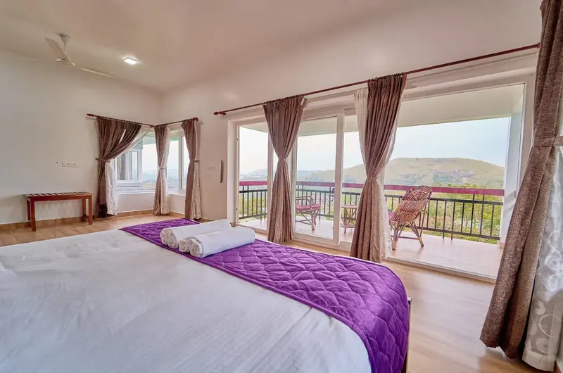 Luxury bedroom opening to private scenic balcony at Priyas Villa Vagamon