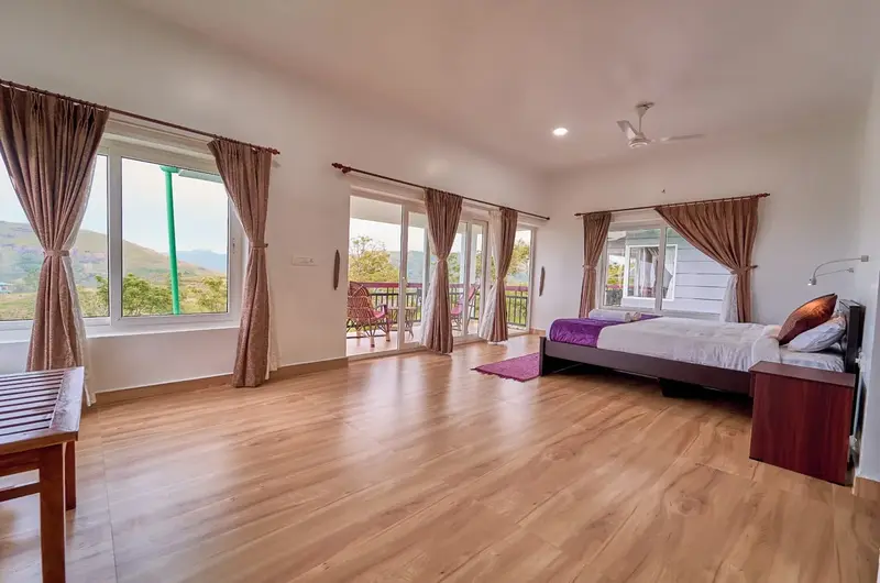 Spacious master bedroom with wooden flooring at Priyas Villa Vagamon