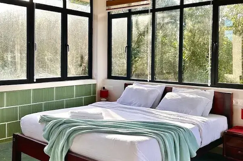 Cozy deluxe bedroom with large windows overlooking green view at 8.5 Acres Vagamon