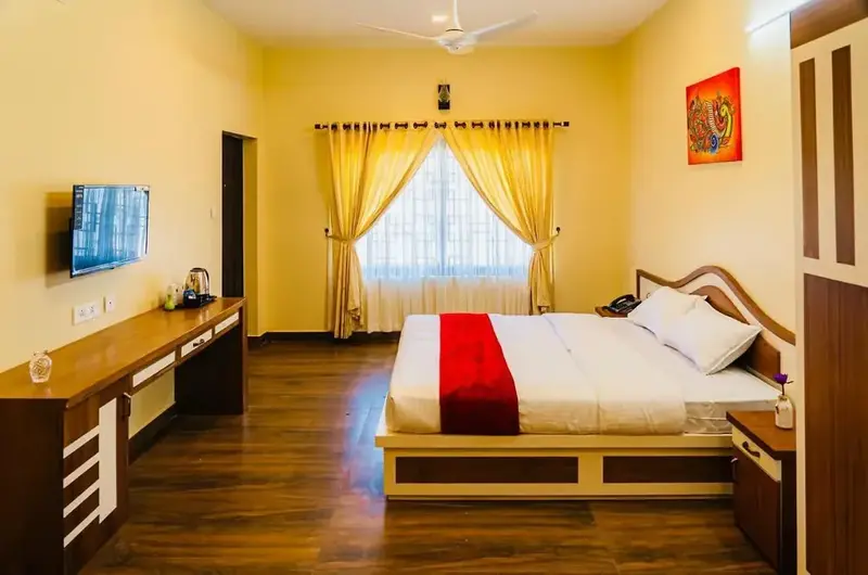 Deluxe resort bedroom featuring double bed, wooden flooring, and modern wall-mounted TV at Vagamon Vagashore