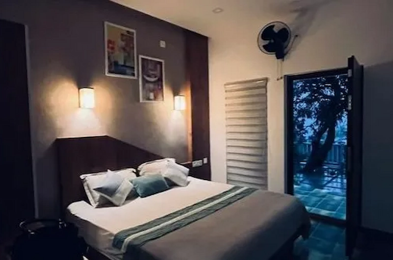 Comfortable bedroom suite featuring warm bedside wall lights and large glass doors at Willow House Cottages