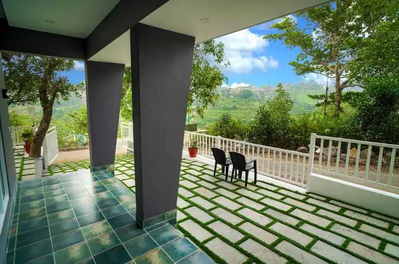 Outdoor tiled patio seating area with a scenic green garden view at Willow House Cottages
