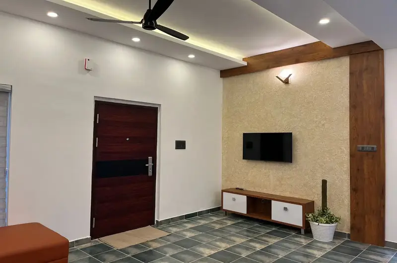 Cozy bedroom with wooden accent paneling, wall-mounted TV, and ceiling fan at Willow House Cottages