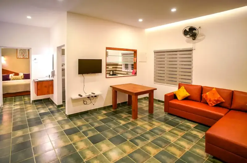 Spacious living area featuring orange sectional sofa and elegant wall decor at Willow House Cottages