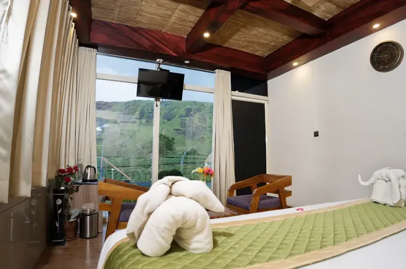 Luxury resort bedroom featuring decorated bed, wooden ceiling paneling, and large windows at Ice Hills Resort