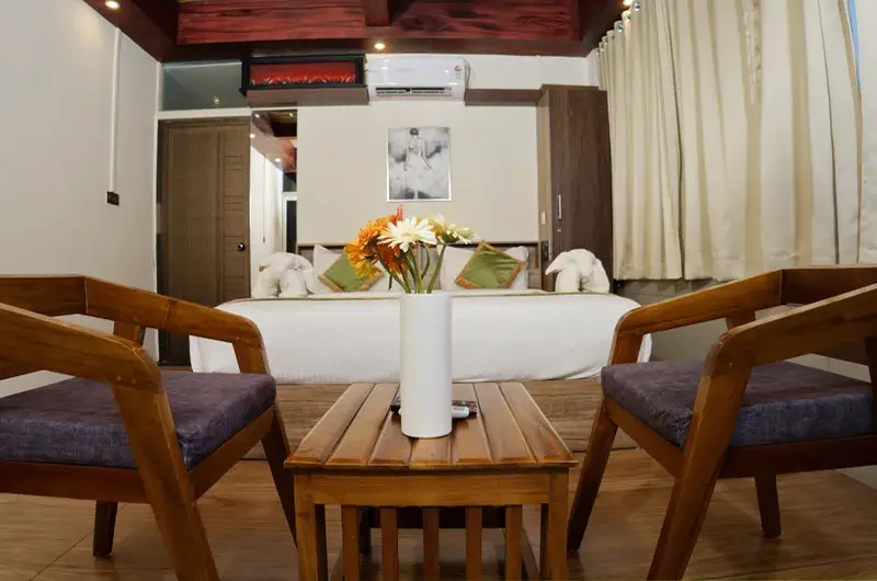 Cozy indoor seating lounge with wooden armchairs, small coffee table, and scenic hill view at Ice Hills Resort