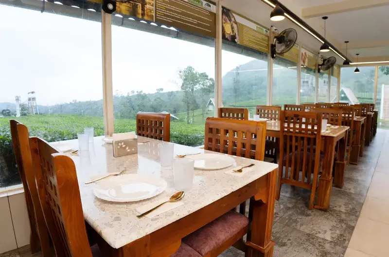 Spacious resort dining area with wooden tables and glass windows overlooking green hills at Ice Hills Resort