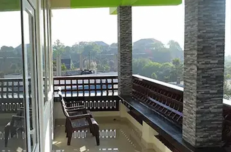 Private balcony seating area overlooking scenic mist-covered hills at Vaga View Residency