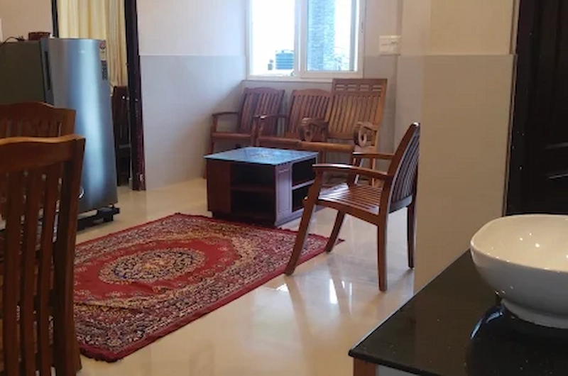 Cozy indoor living lounge area with wooden seating and floor rug at Vaga View Residency