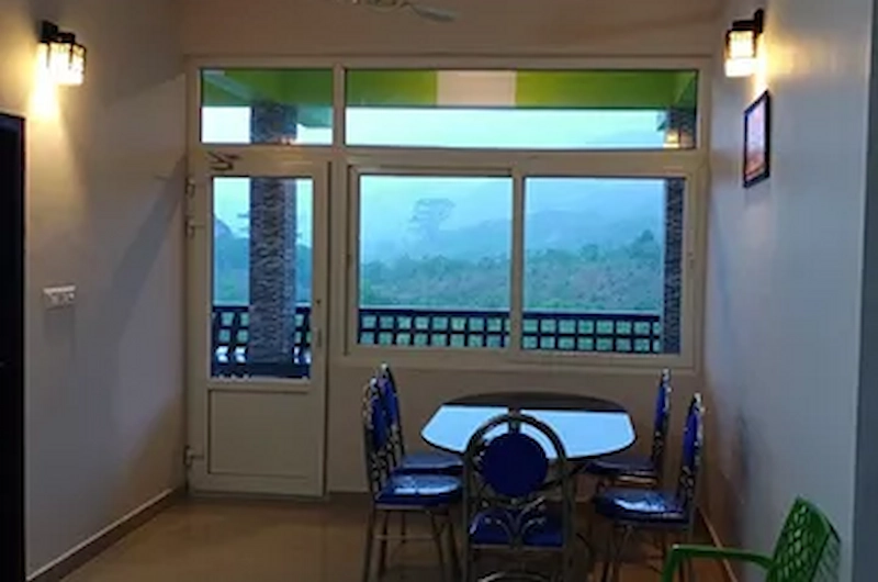 Indoor dining area with glass windows overlooking scenic hill views at Vaga View Residency
