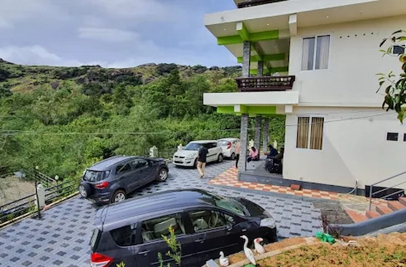 Side exterior view of Vaga View Residency surrounded by green hills in Vagamon
