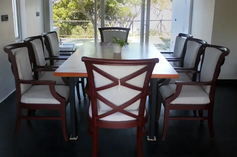 Elegant indoor dining area with wooden table, plush chairs, and large window at Vagamon Exotica