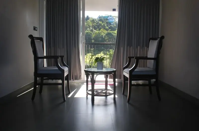 Cozy in-room seating area with armchairs facing large window with scenic nature view at Vagamon Exotica