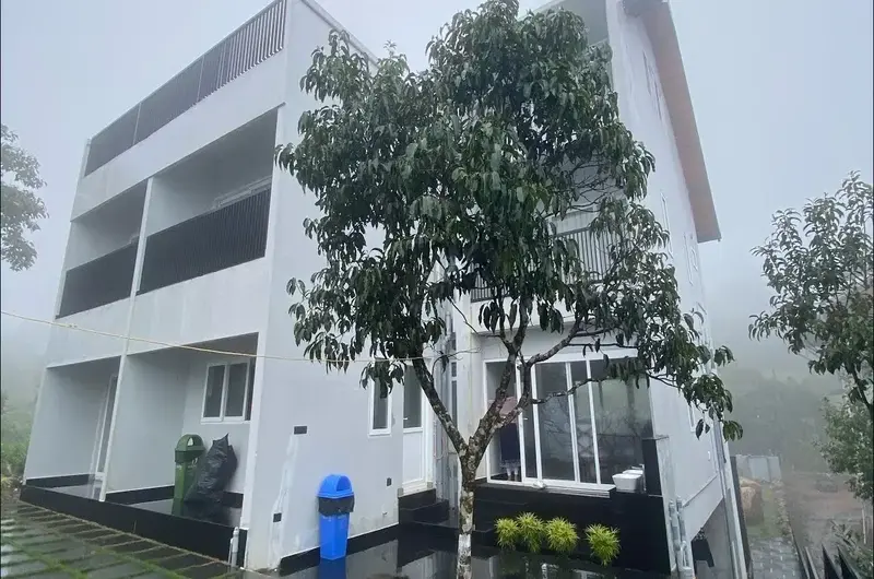 Front exterior view of white multi-story villa building surrounded by trees at Vagamon Exotica