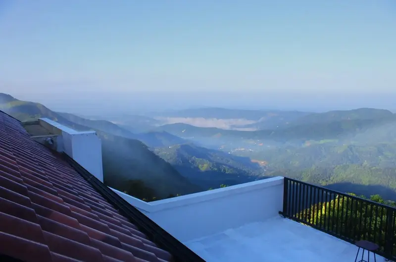 Rooftop terrace overlooking mist-covered valleys and green hills at Vagamon Exotica