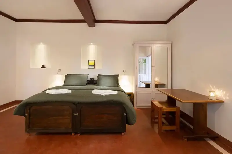 Comfortable bedroom suite featuring dark wooden ceiling beams, cozy bed, and study desk at Ghats Edge