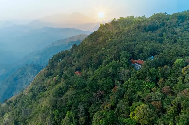 Scenic view of mist-covered green hills and valley at sunrise at Ghats Edge in Vagamon