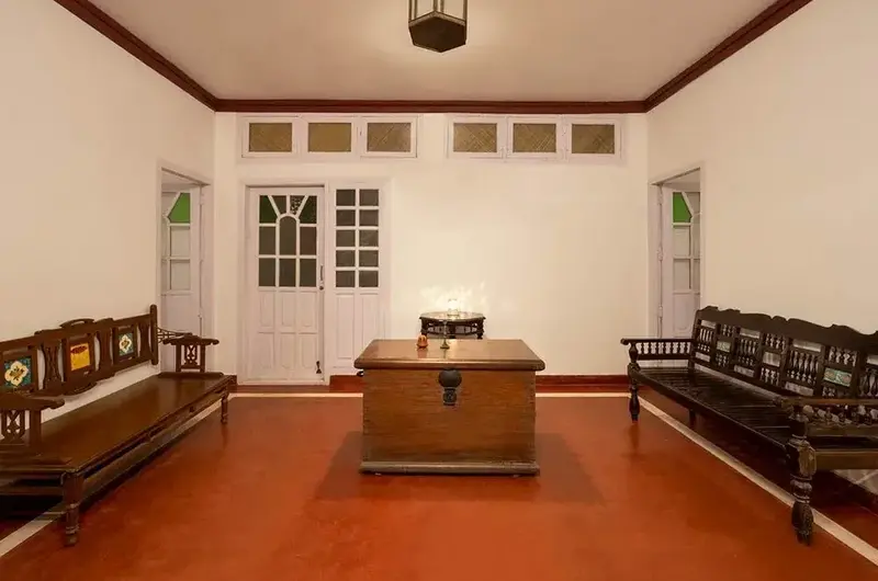 Spacious living hall interior with traditional wooden benches and red-tiled flooring at Ghats Edge