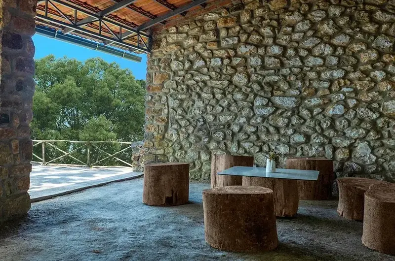 Outdoor lounge area featuring stone wall accent and wooden seating at Ghats Edge