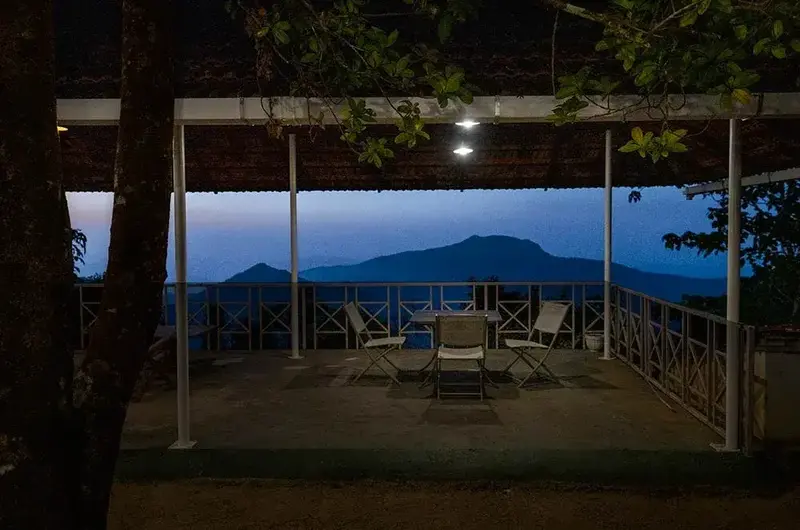 Balcony seating lounge with glass railing offering panoramic mountain views at Ghats Edge